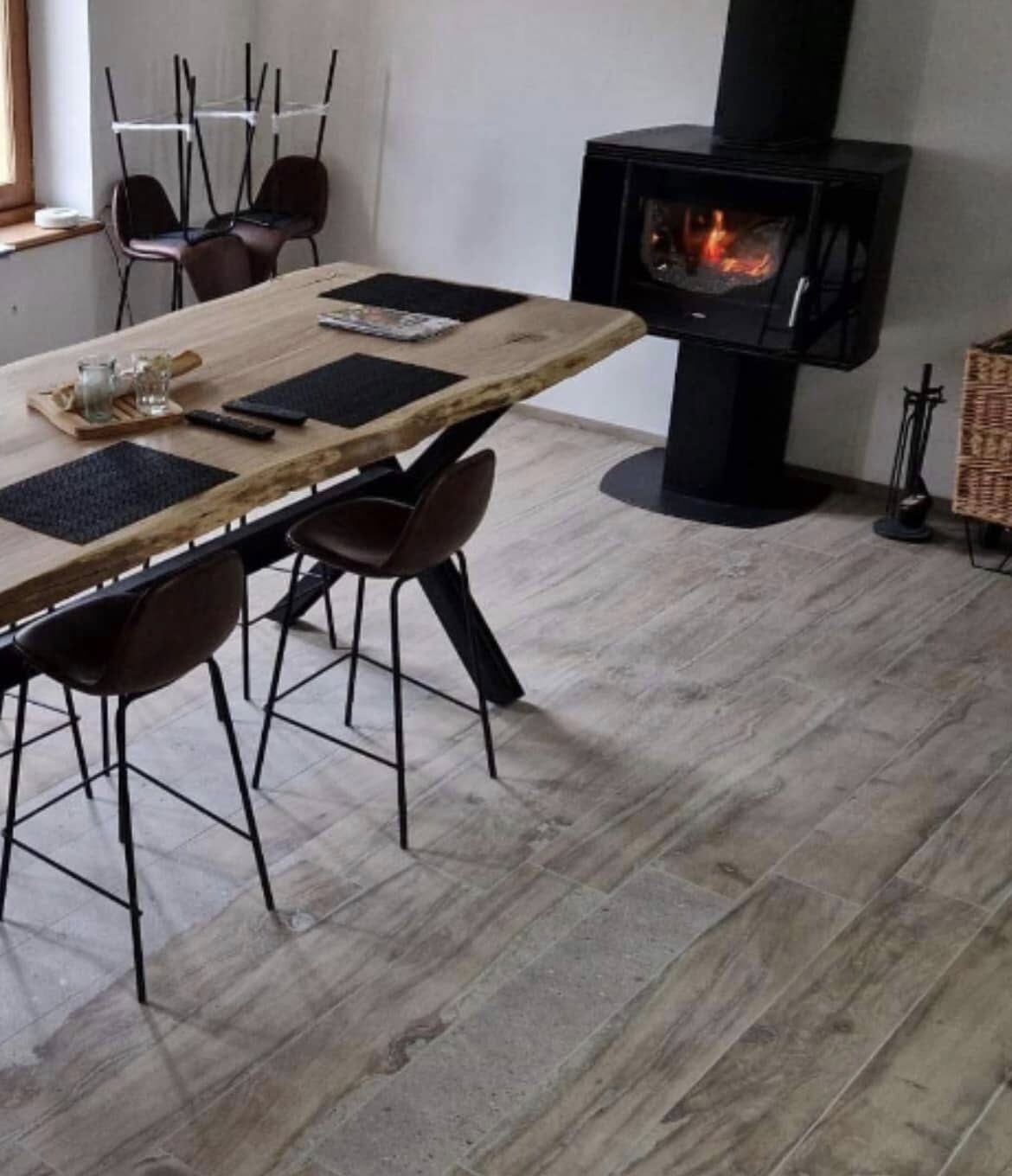 Salon et salle à manger carrelés en lames claires, poêle à bois au fond