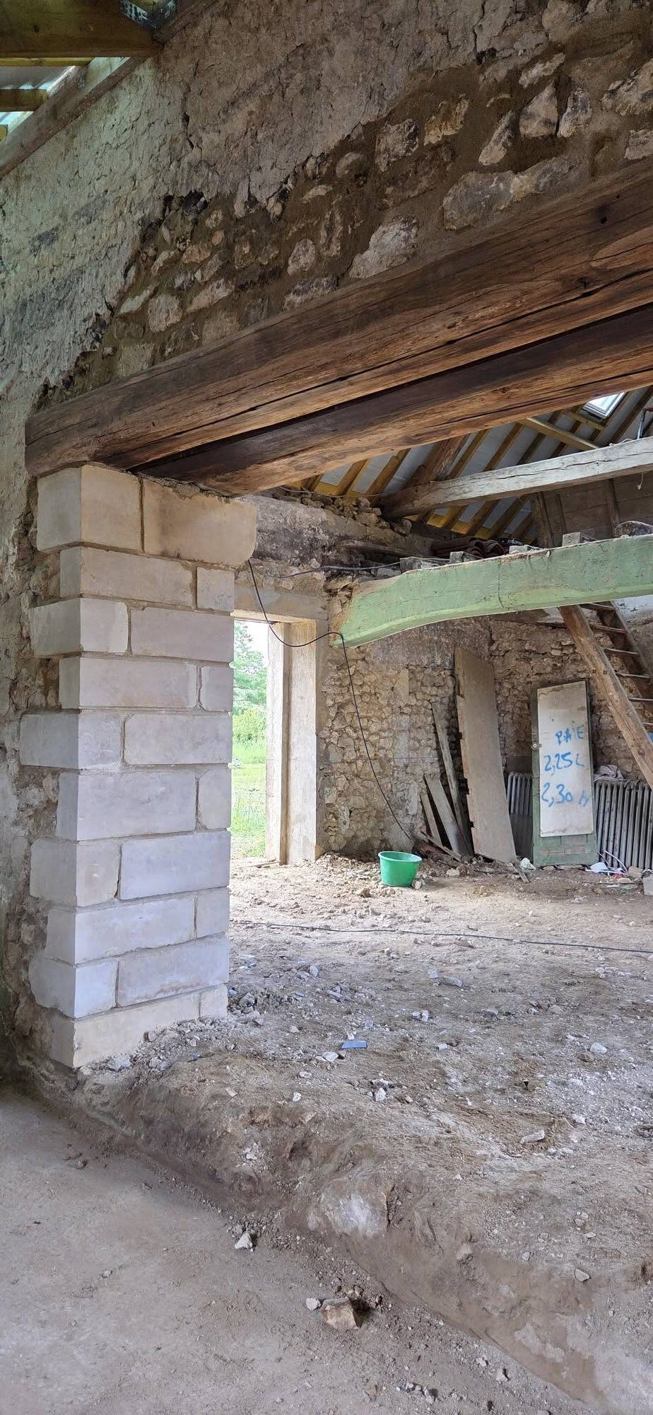 Pilier en pierre et poutre de chêne dans une grange en chantier