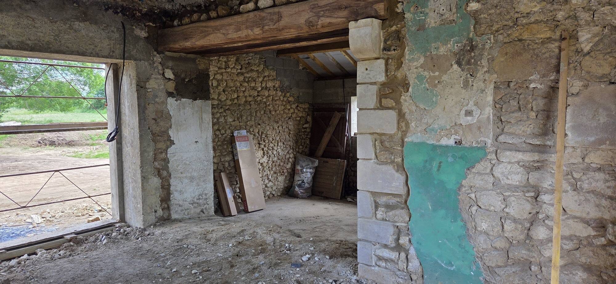 Grange en rénovation : ouverture percée, poutre et pierres apparentes