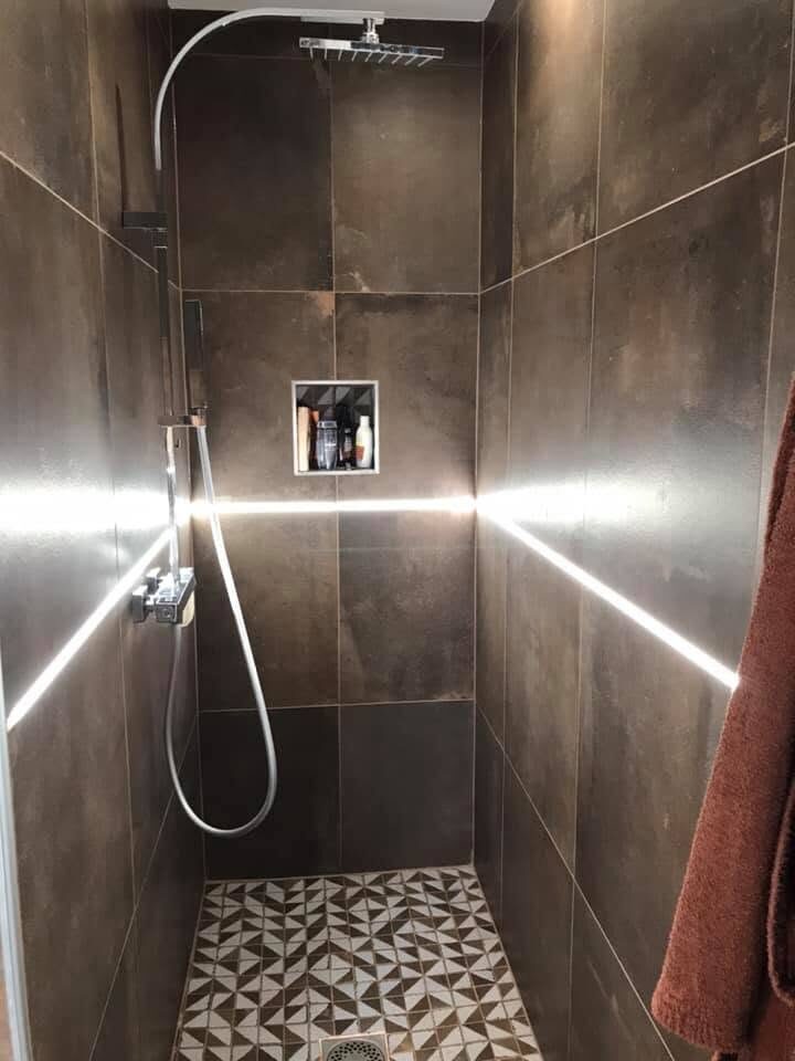 Douche carrelée en grands carreaux sombres, niche intégrée et sol à motifs