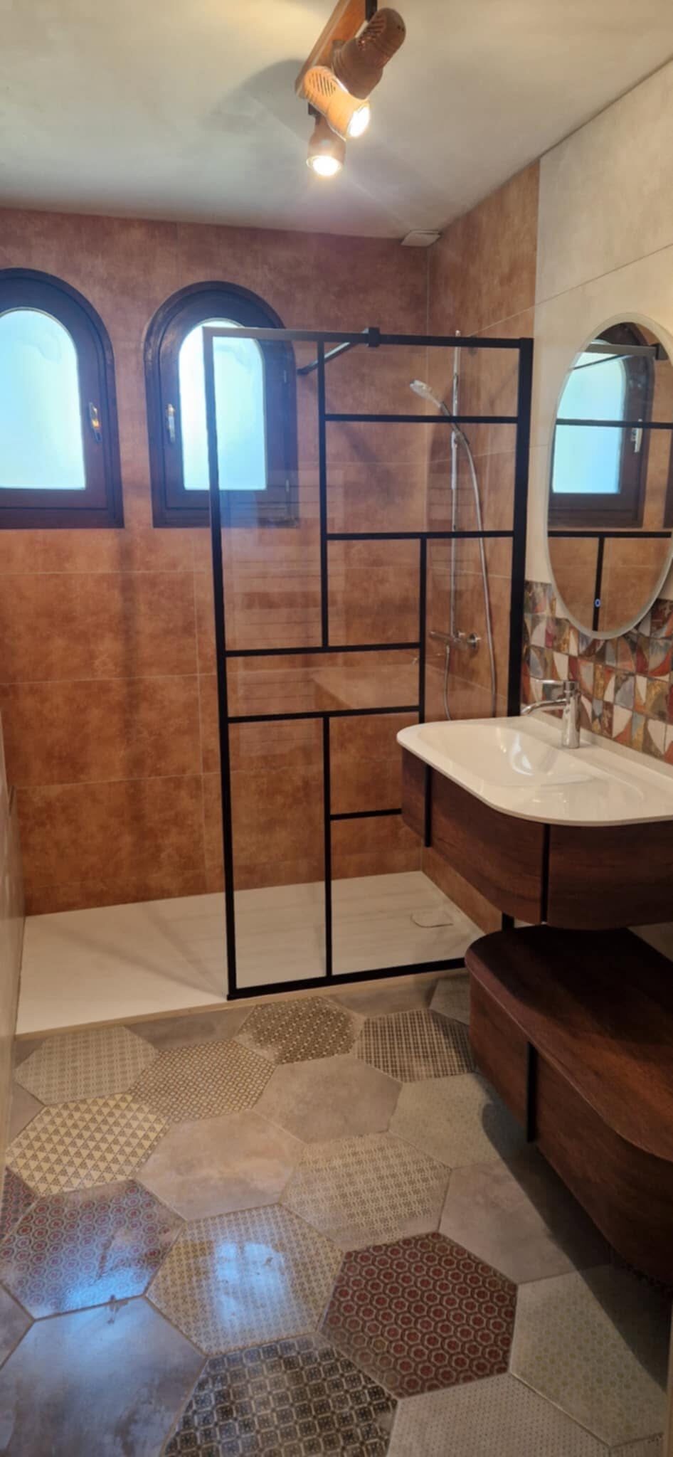 Salle de bain avec paroi de douche vitrée à cadre noir et sol de carreaux hexagonaux