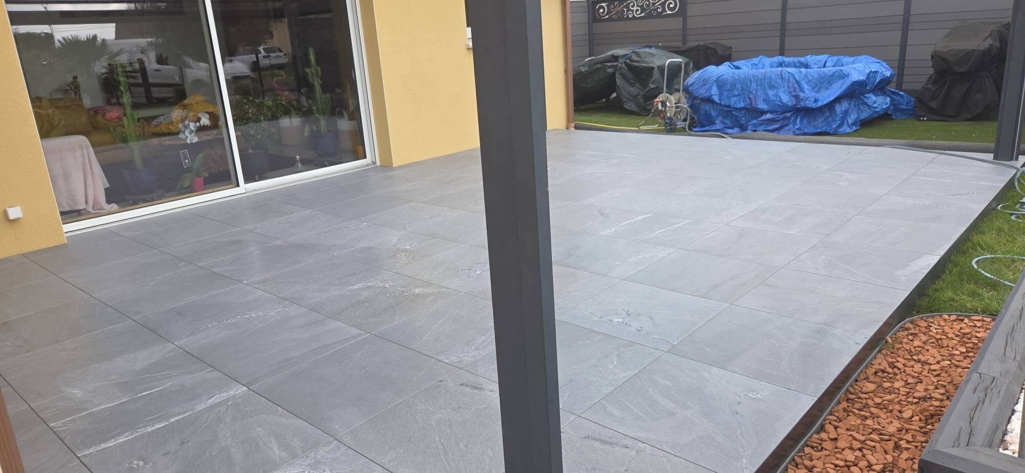 Terrasse en carreaux gris grand format devant une baie vitrée