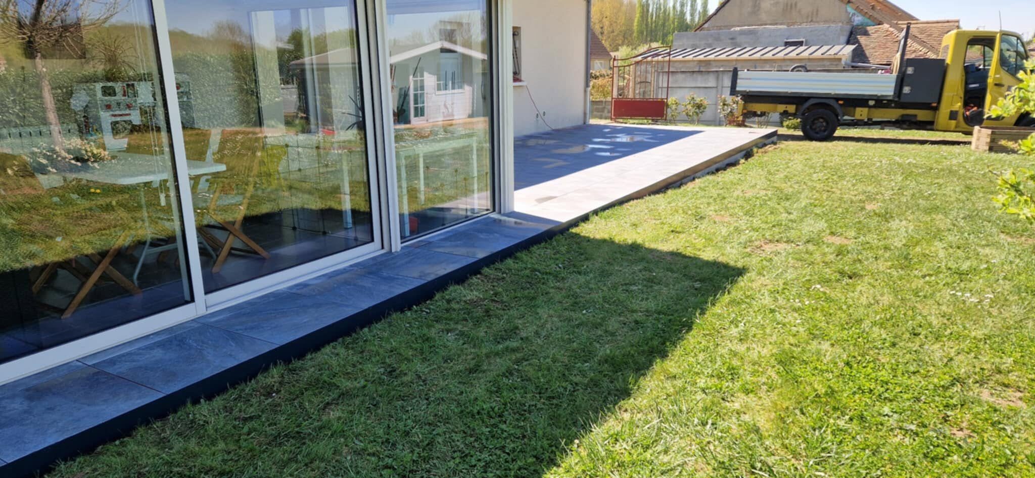 Terrasse carrelée en gris anthracite bordant une pelouse